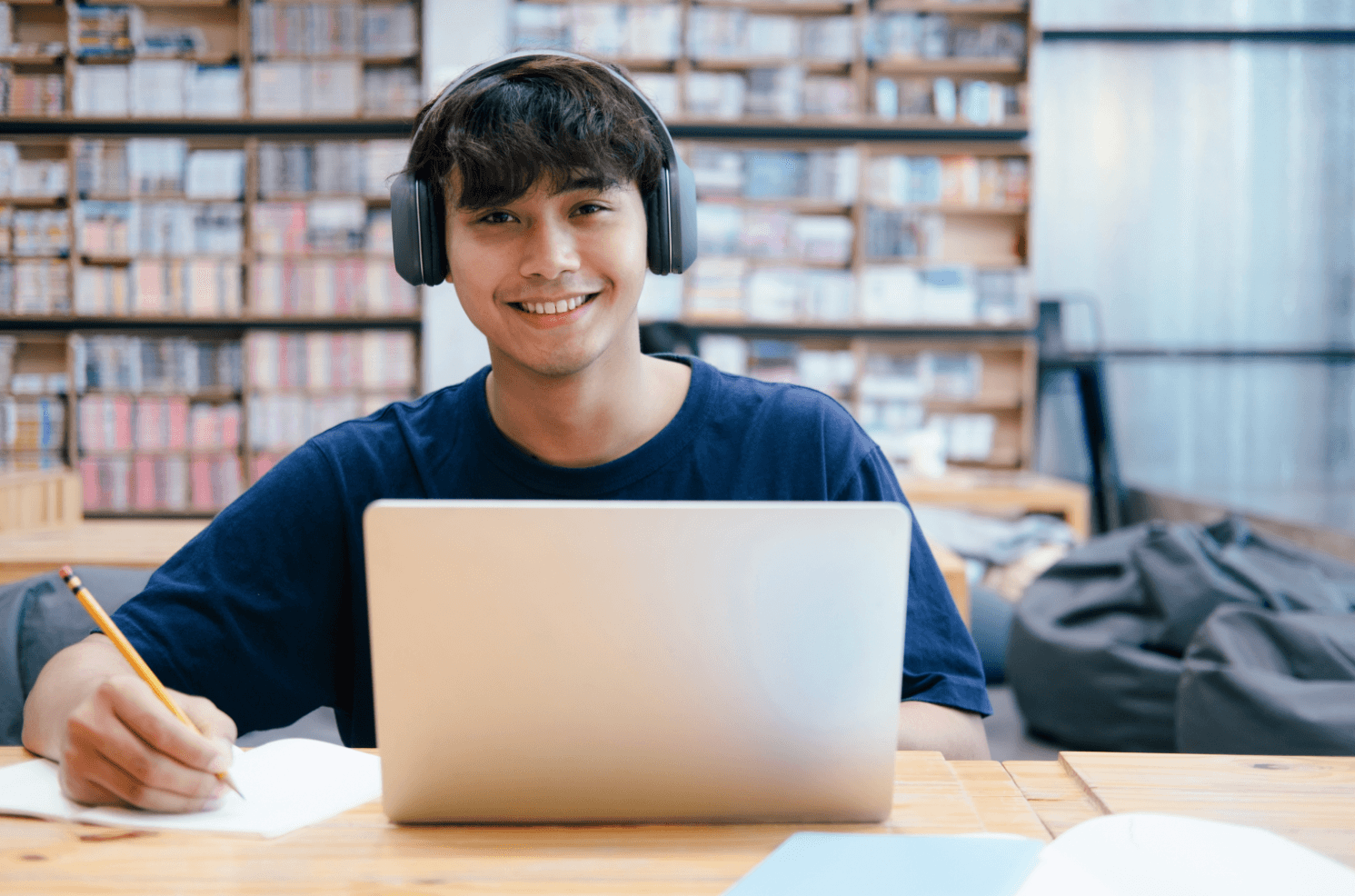 Young College Student Studying in Library with Laptop